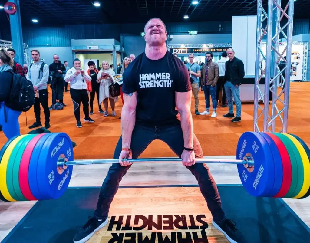 man sumo deadlifting a full bar using hammer strength plates