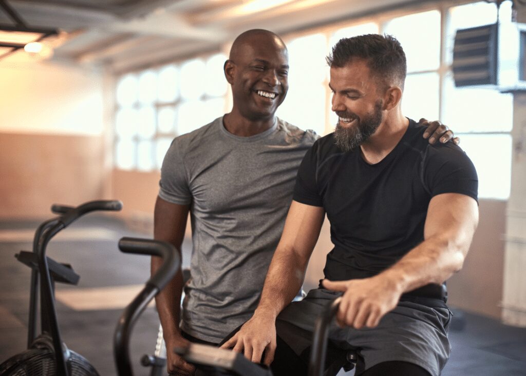 man patting other man on the back after a solid cardio session on a bike