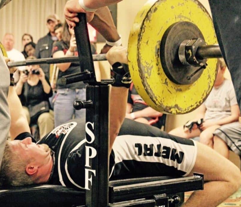 man benching in a powerlifting meet while using a power bar