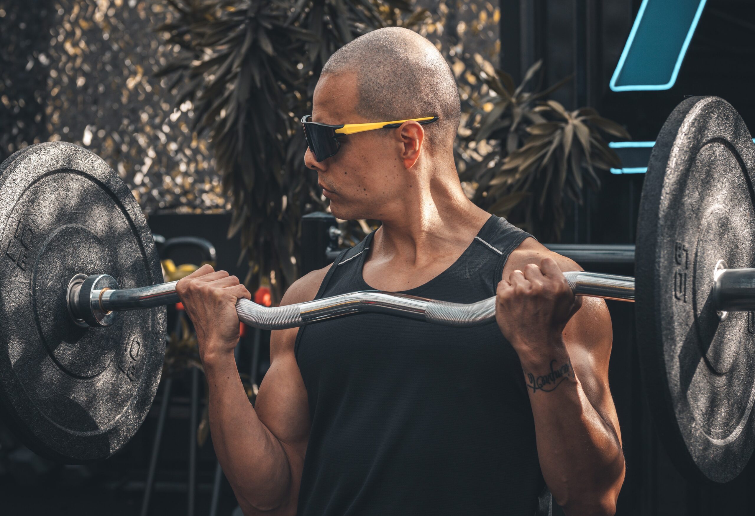 man with sunglasses curling ez curl barbell