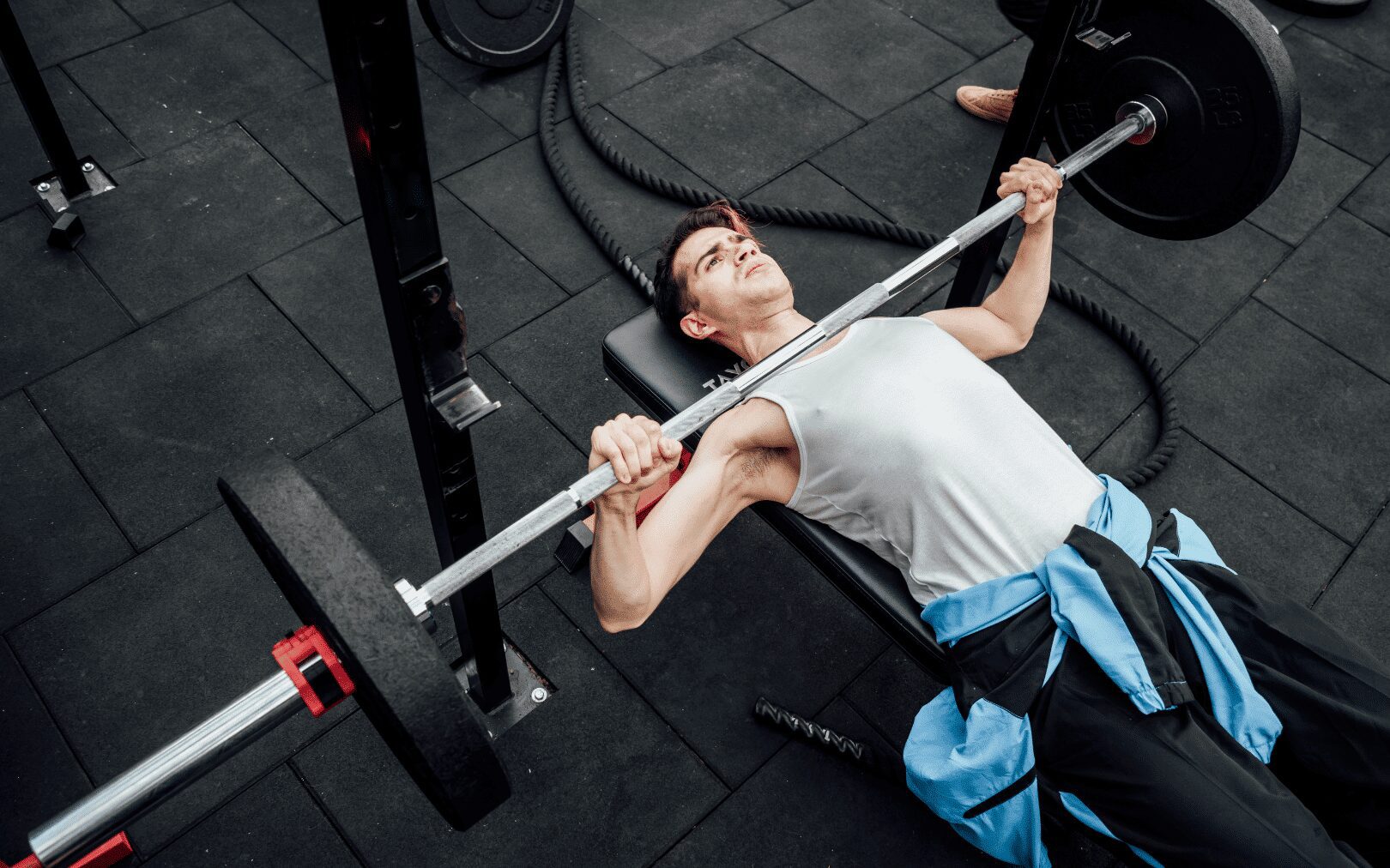 man doing the bench press with a traditional barbell