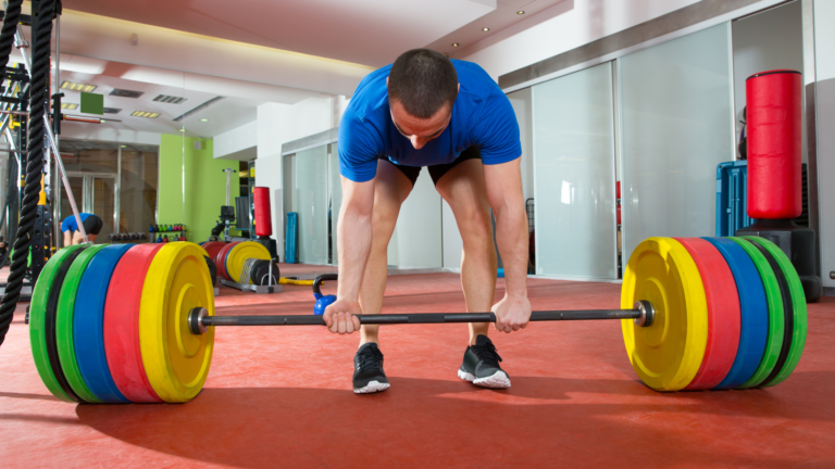 man getting ready to deadlift heavy barbell with colorful bumper plates