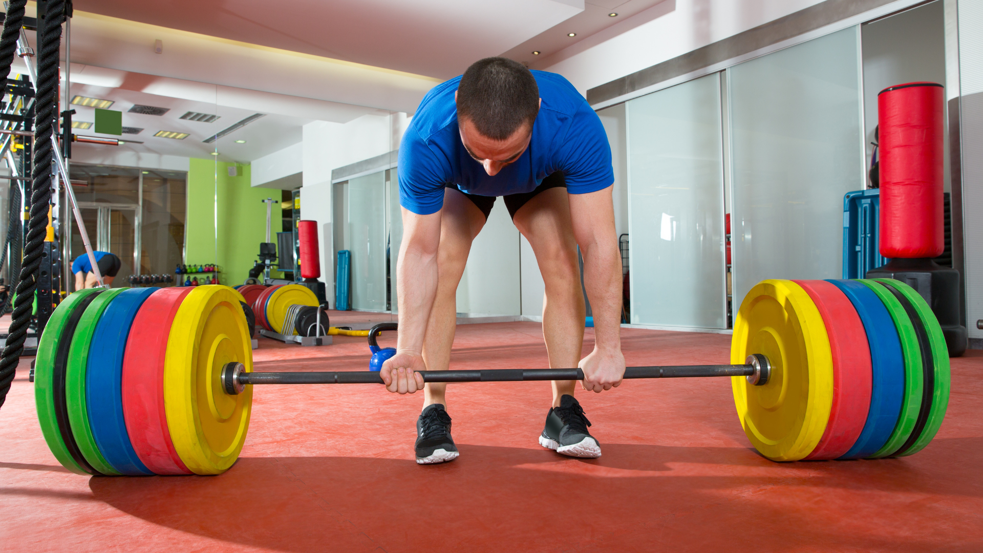 man getting ready to deadlift heavy barbell with colorful bumper plates