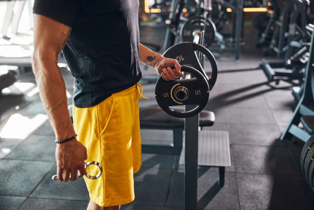 man adding a weight to barbell