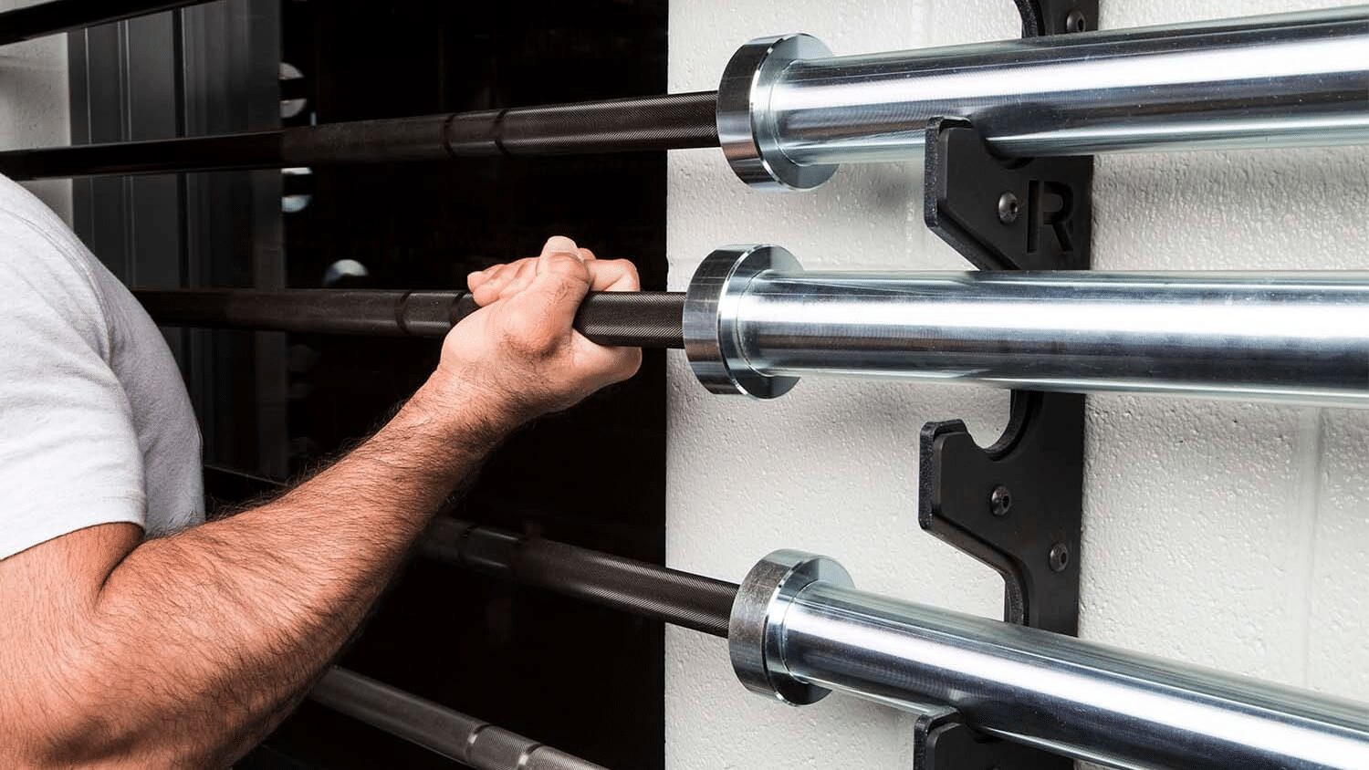 man taking barbell off of horizontal storage