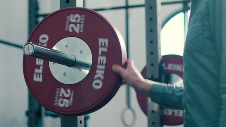 man putting plate on olympic bar
