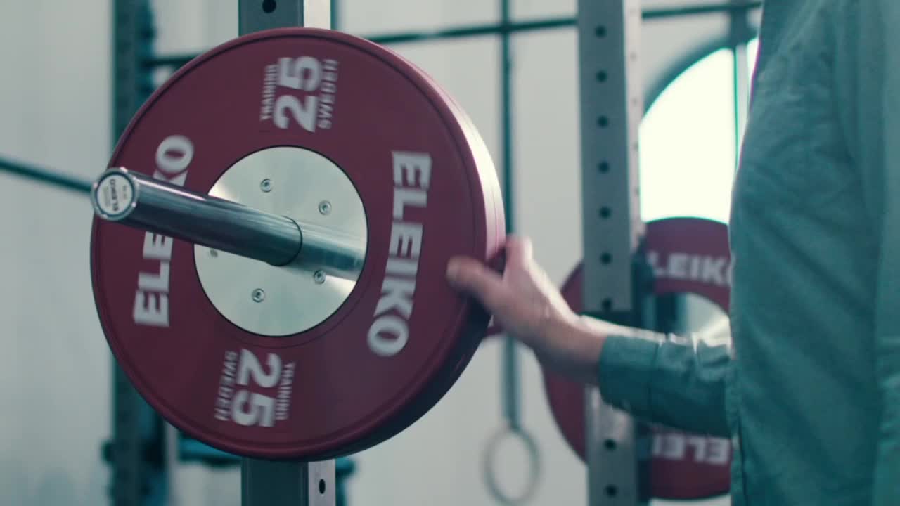 man putting plate on olympic bar