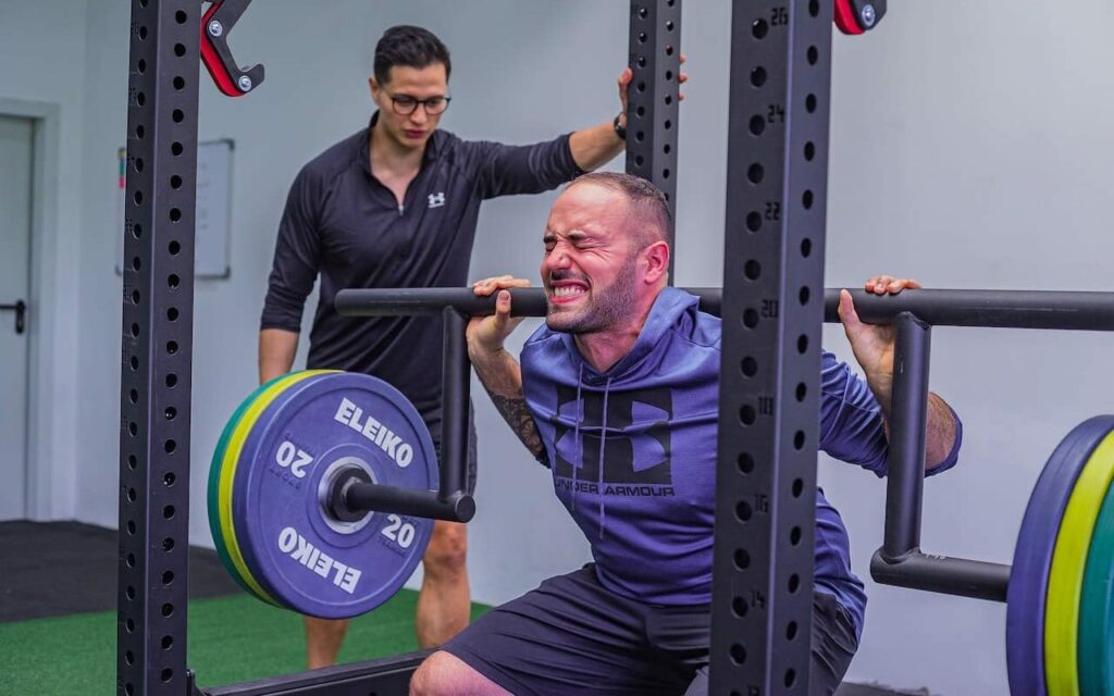 man squatting with colorful bumper weight plates