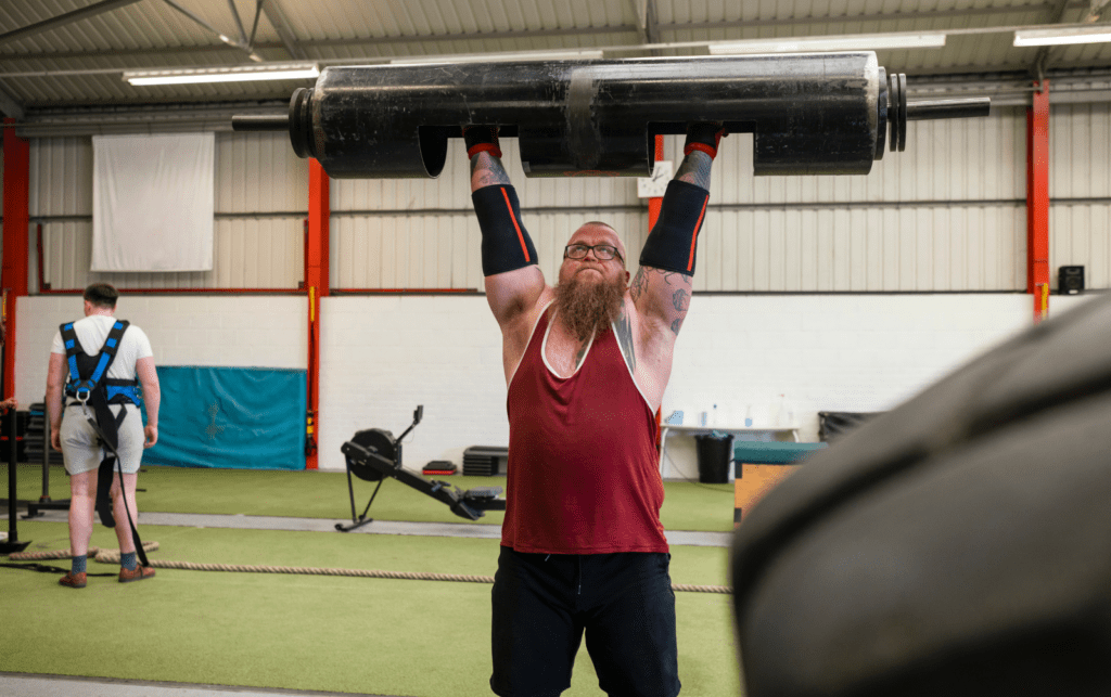man lifting log bar overhead
