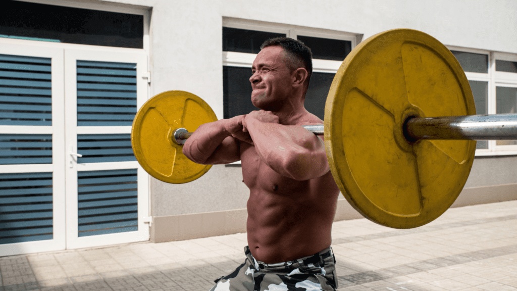 shirtless man doing front squats with arms crossed