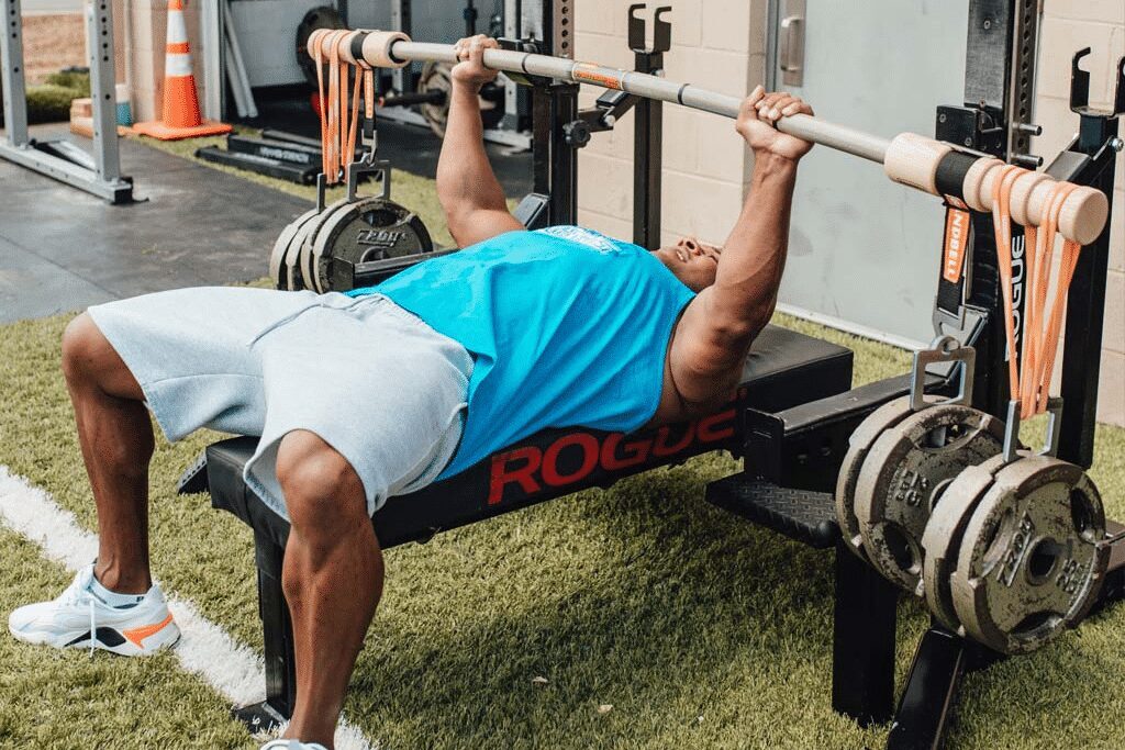 man performing the bench press with a bamboo bar