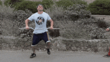 man hopping around holding empty curl bar